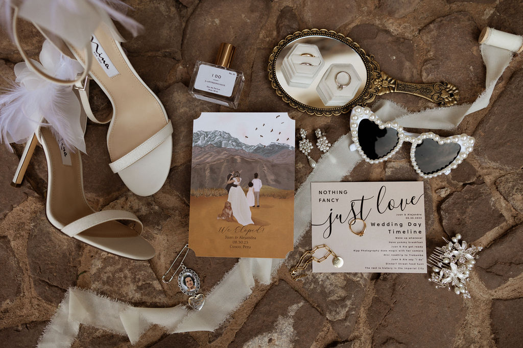 Wedding flatlay of couple getting married in peru featuring wedding invitation, wedding rings, sunglasses, wedding shoes, and other fine details
