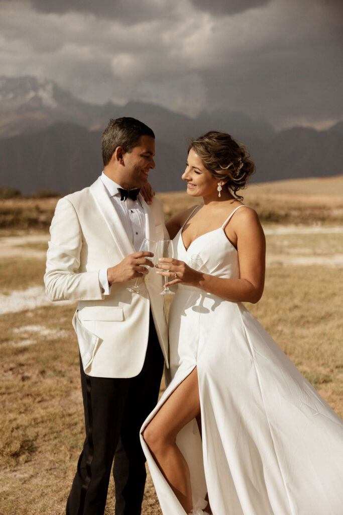 Bride and groom photos in the mountains of Peru after their wedding ceremony holding glasses of champagne
