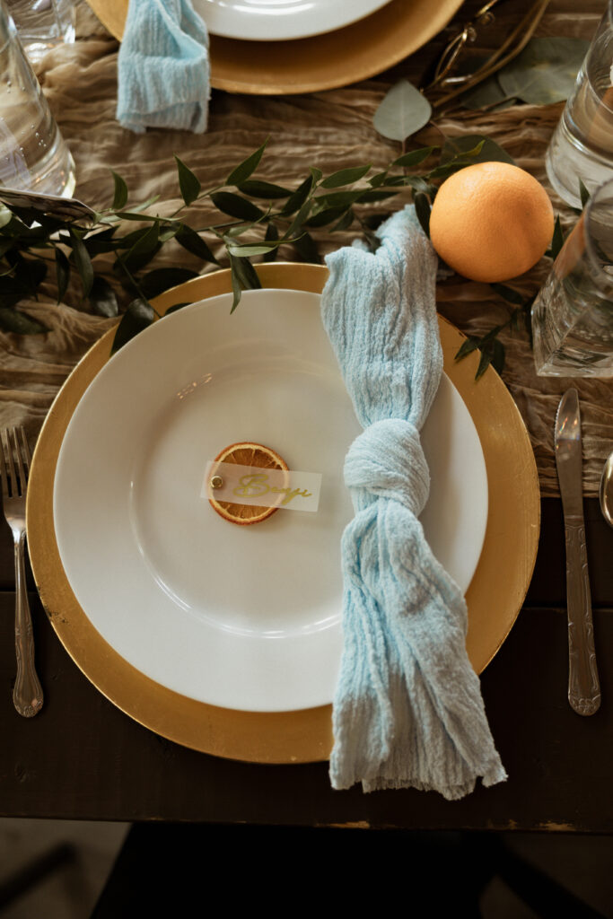 wedding detail photo from florida wedding of the table set up with plates, greenery, and oranges