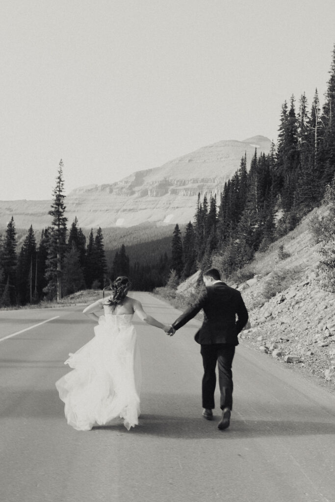 elopement at Glacier National Park of bride and groom running down the street together