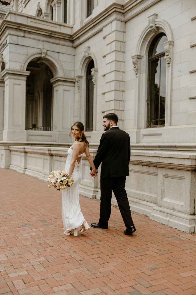 city elopement portrait of bride and groom walking together down the sidewalk