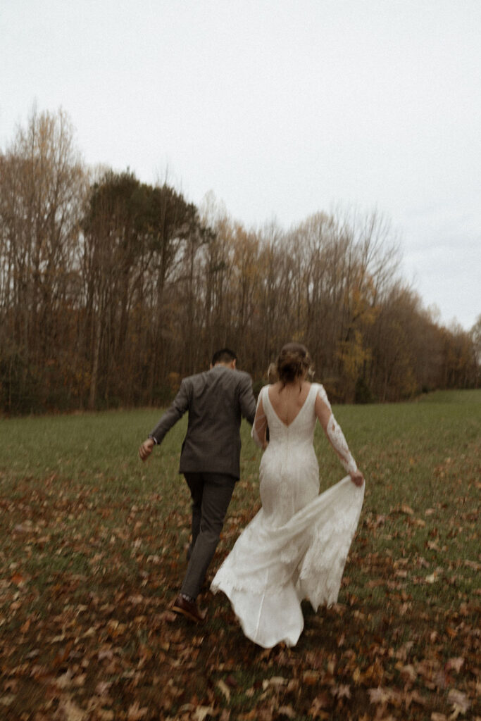 fall outdoor wedding portraits of bride and groom holding hands running together