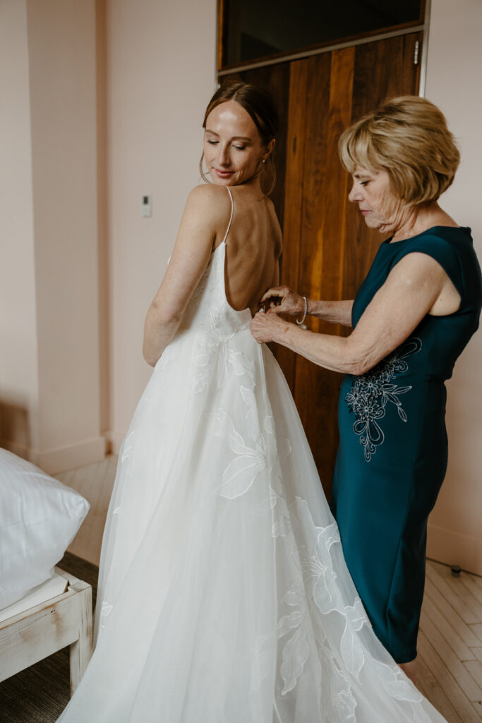 Bridal getting ready photo of brides mother helping her with the back of her dress