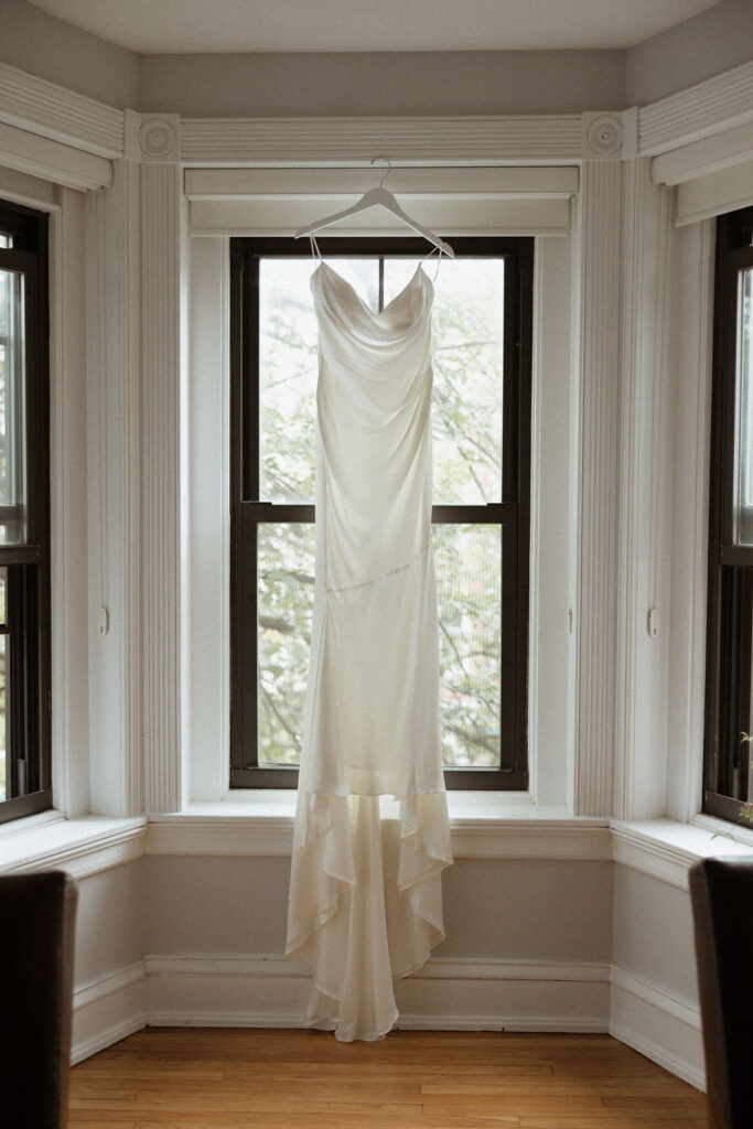 long white wedding dress hanging from the window