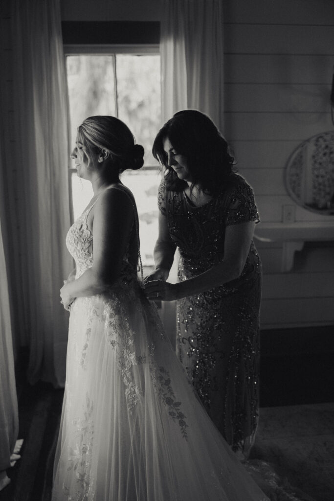 bridal getting ready photos of mother helping daughter put on her wedding dress