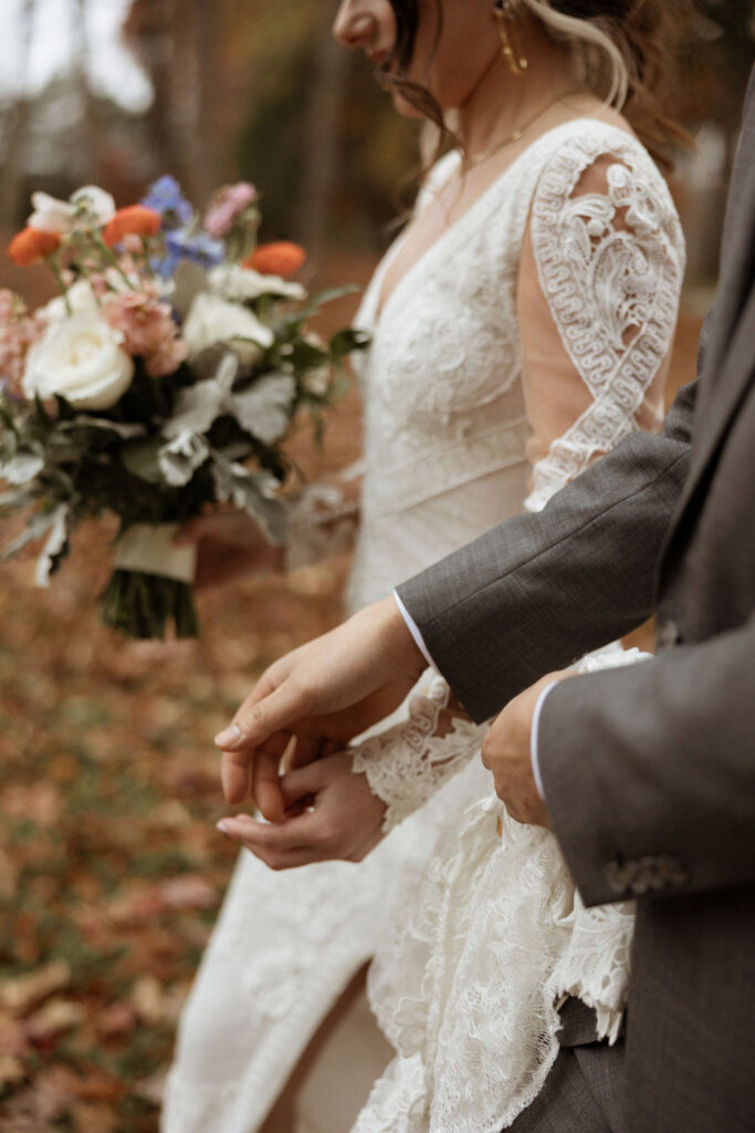 detail wedding photo of bride and groom holding hands walking together