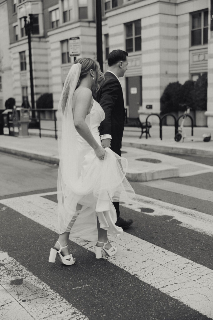 bride and groom holding hands together in the city crossing the street